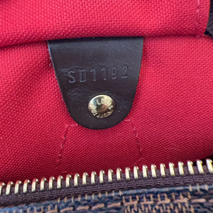 Red bag with a black leather patch and gold zipper, featuring a visible brand logo.