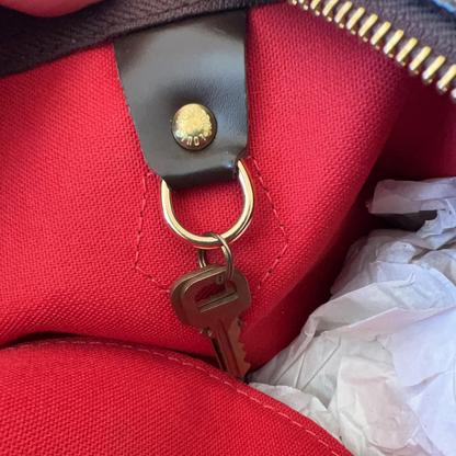 Close-up of a red bag with a gold zipper pull and keychain.