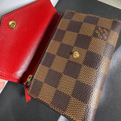 Red wallet and brown checkered wallet with gold buttons on a gray surface