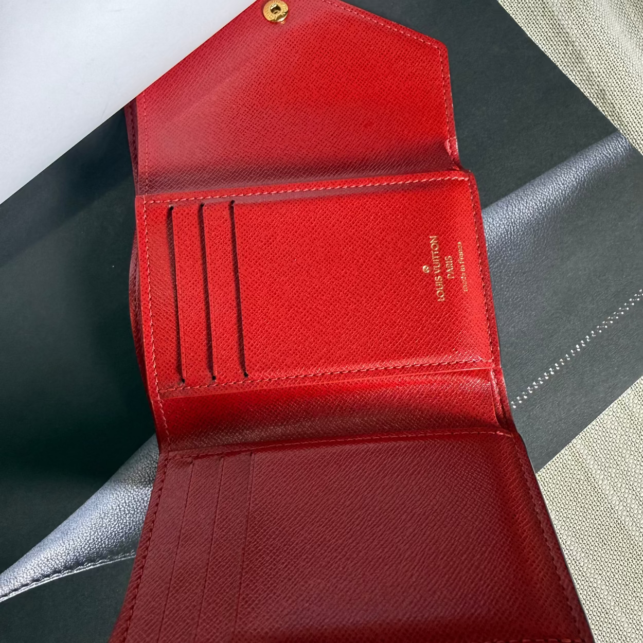 Red wallet with gold accents on a gray surface