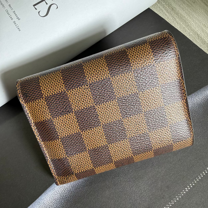 Checkered wallet on a dark surface with a book in the background