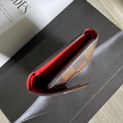Close-up of a red and gold wallet on a black surface with a book titled 'ZIP CODES' in the background.