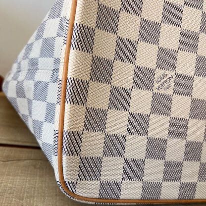 Checkered patterned bag with visible brand logo on a wooden surface