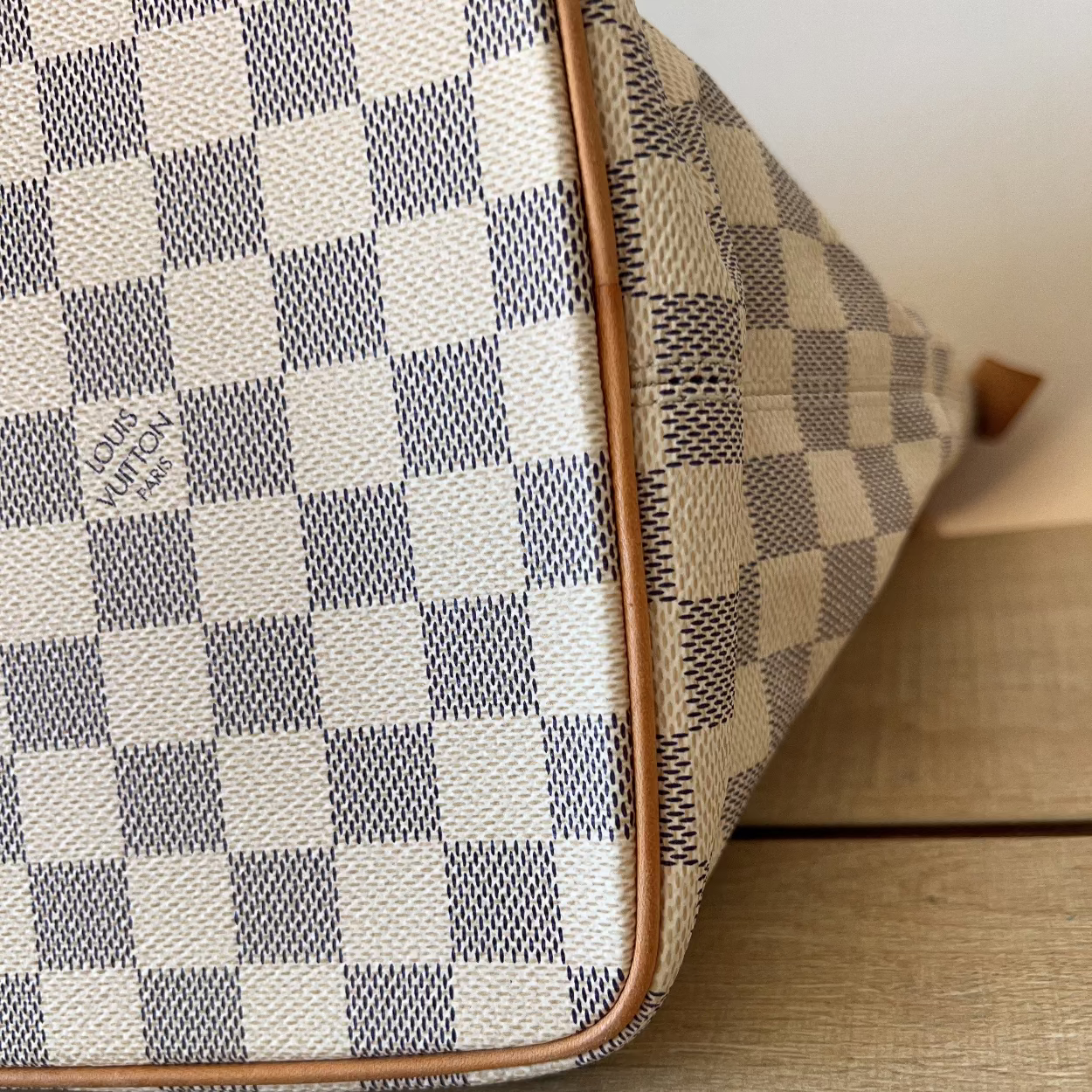 Checkered handbag with visible brand logo on a wooden surface