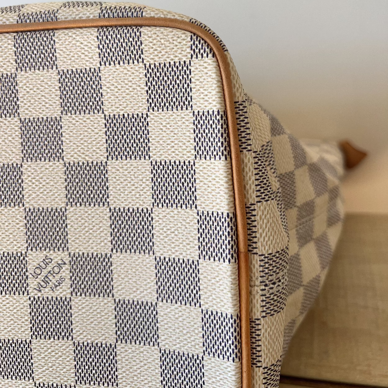 Checkered patterned suitcase with visible brand name on a neutral background