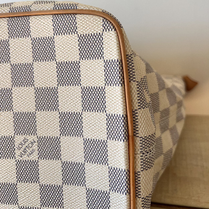 Checkered patterned suitcase with visible brand name on a neutral background