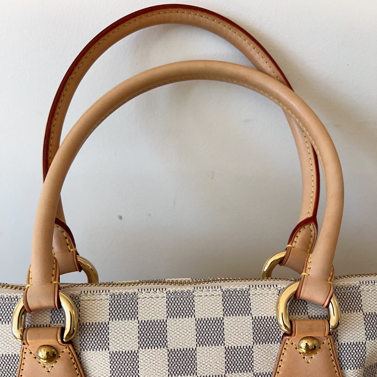 Designer handbag with checkered pattern and gold hardware on a white background