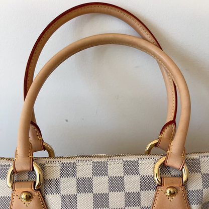 Designer handbag with checkered pattern and gold hardware on a white background