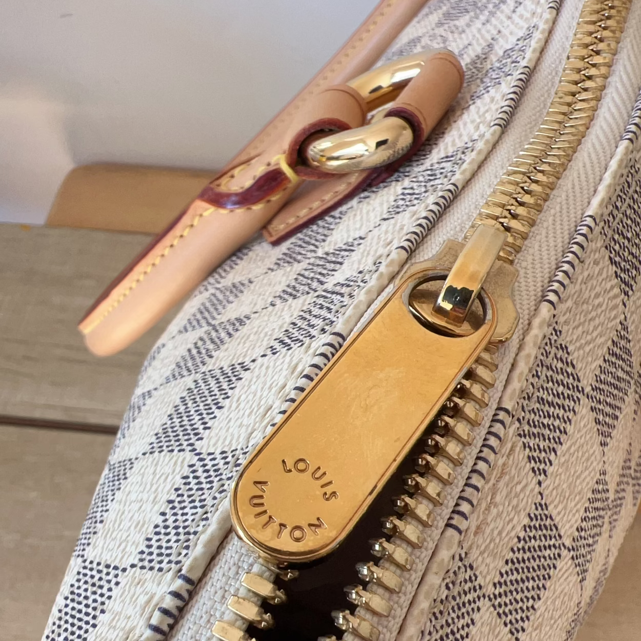 Close-up of a Louis Vuitton handbag zipper with checkered pattern