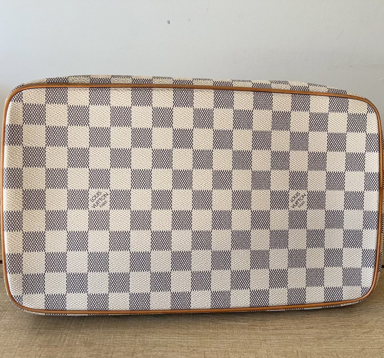 Checkered patterned pouch on a wooden surface with a neutral background