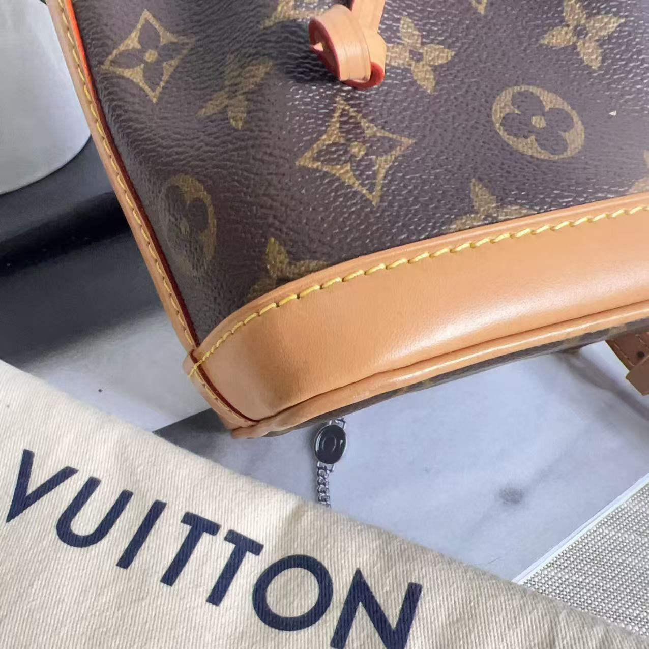 Close-up of a Louis Vuitton handbag with monogram pattern and beige interior lining.