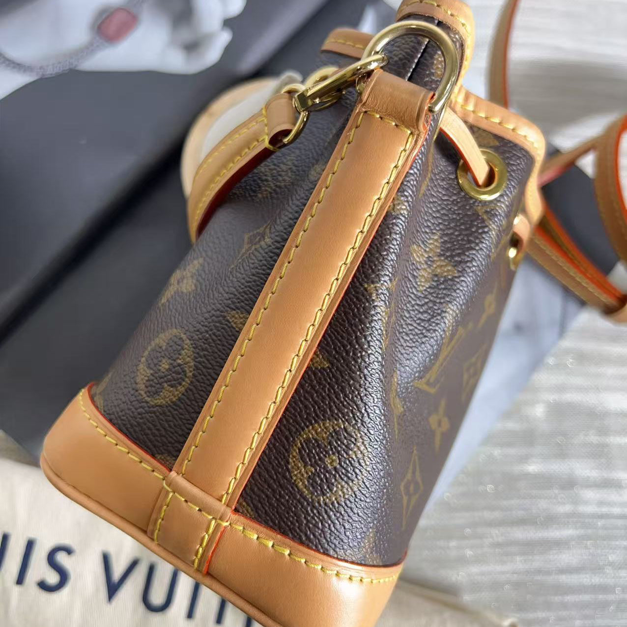 Louis Vuitton handbag with monogram pattern and tan leather trim on a surface.