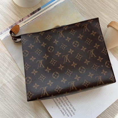 Louis Vuitton patterned notebook on an open book with flowers and a candle in the background