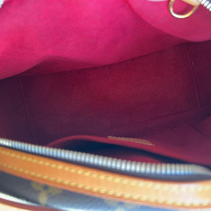 Close-up view of the interior of a handbag, showing a bright pink or magenta suede-like lining, a tan leather zipper trim, and part of a dark patterned exterior.