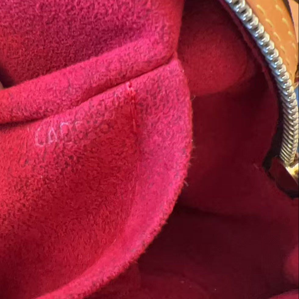 Close-up of a bright pink suede or velvet interior lining of a handbag, with a tan leather trim and silver zipper visible along the top edge.