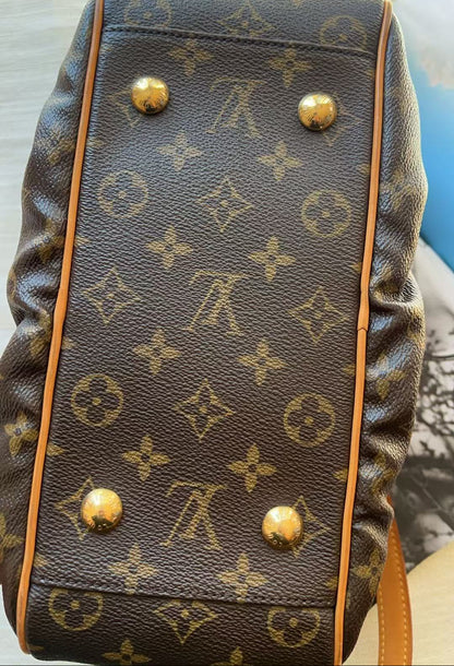 A close-up of a Louis Vuitton monogram canvas bag, showing the dark brown coated canvas with tan monogram motifs, gold-tone metal studs, and light brown leather trim.