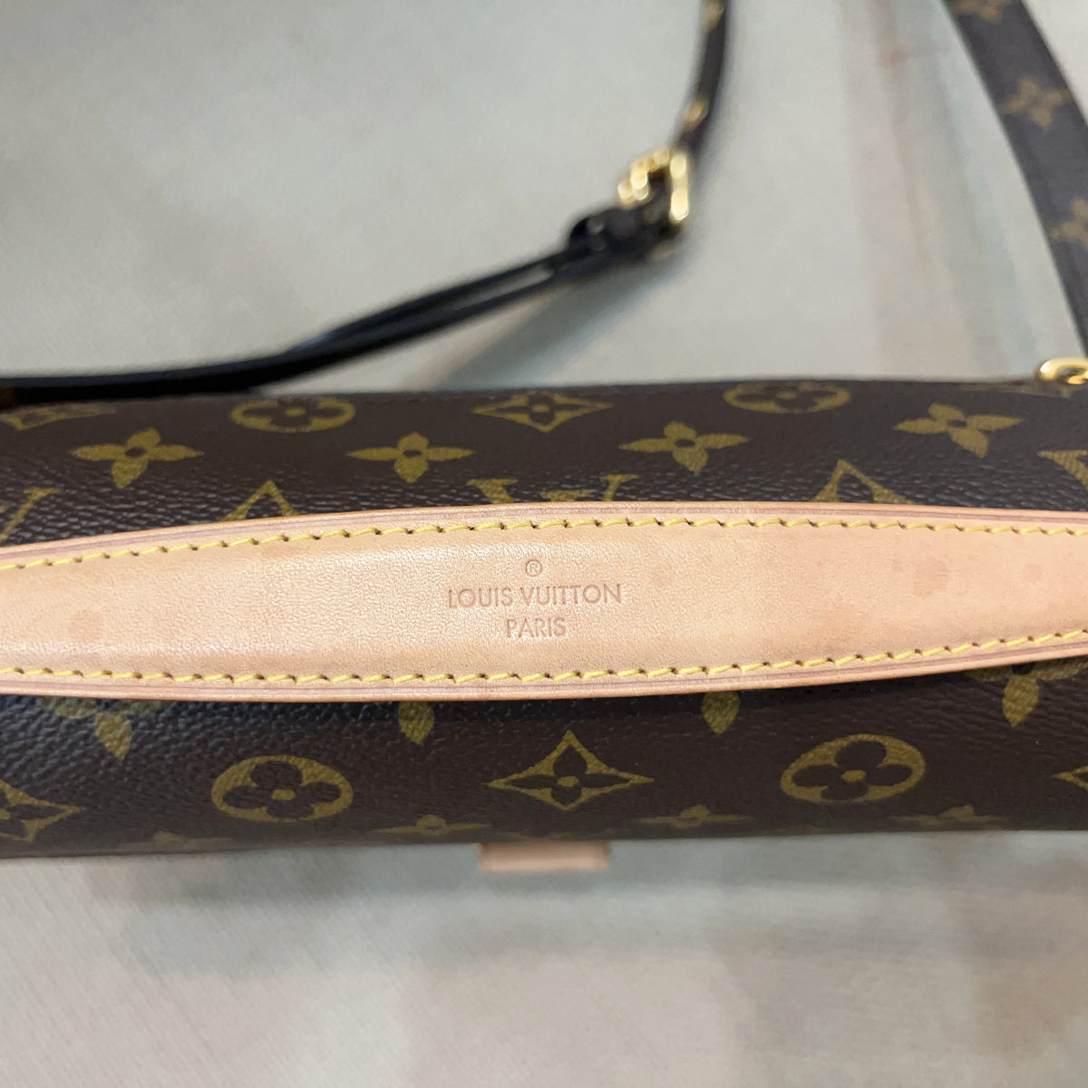 Louis Vuitton monogram canvas shoulder bag in dark brown with tan leather trim and strap, featuring the embossed Louis Vuitton Paris logo on the center leather tab.