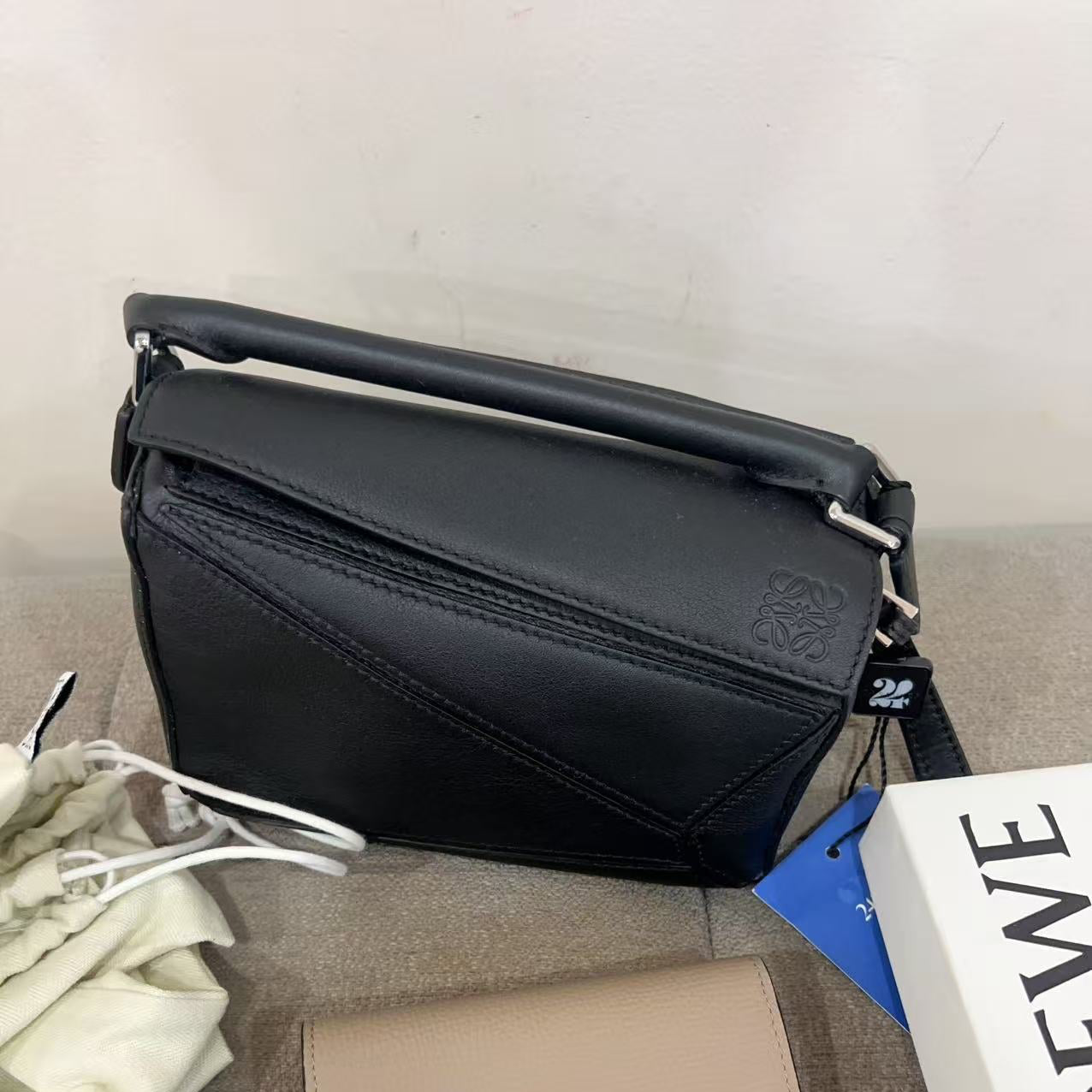 Black handbag and beige wallet on a gray surface with a white background