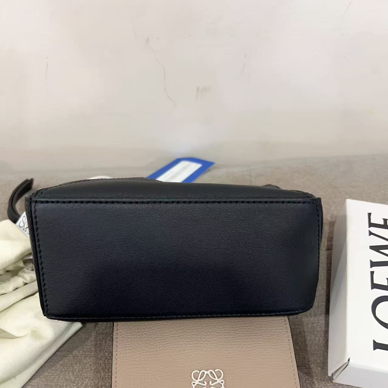 Black handbag and beige wallet with logo on a gray surface