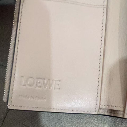 Close-up of a beige leather wallet with 'LOEWE' branding on a gray surface.