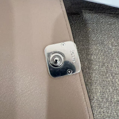 Close-up of a metallic lock mechanism on a beige fabric surface.