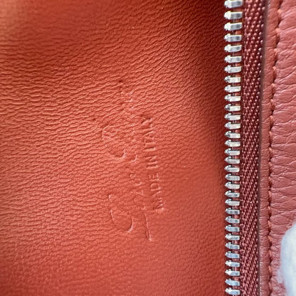 Close-up of a red leather bag with a brand logo and zipper detail.