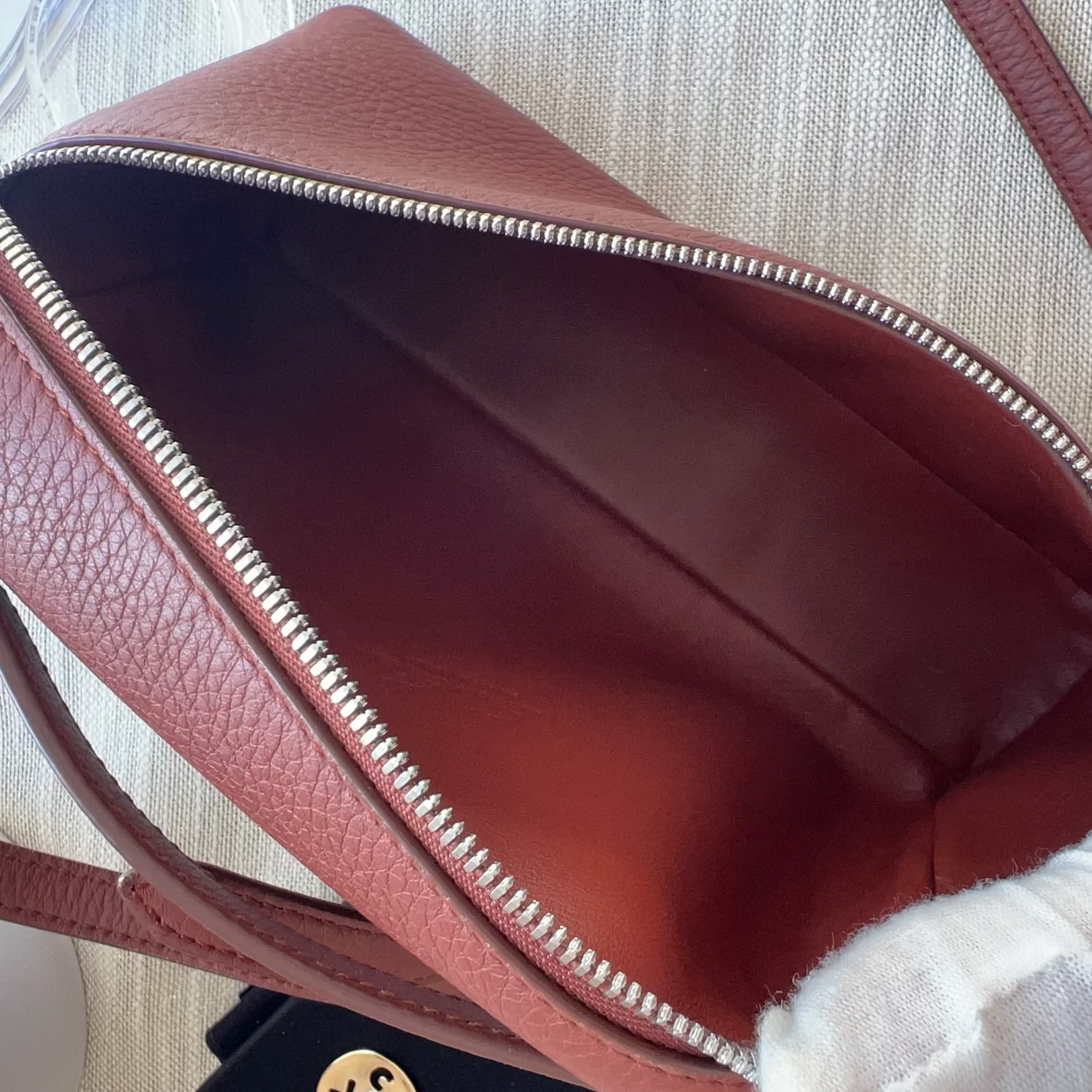 Close-up of a red handbag with a textured surface on a light background