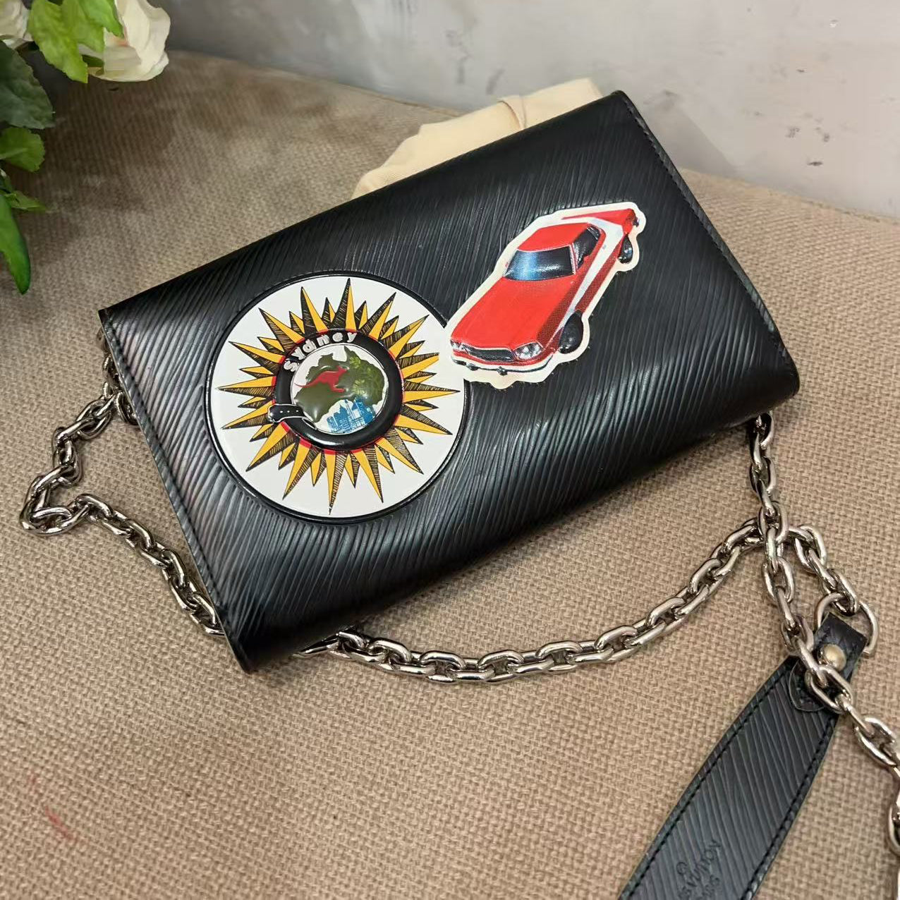 Black handbag with colorful stickers on a textured surface