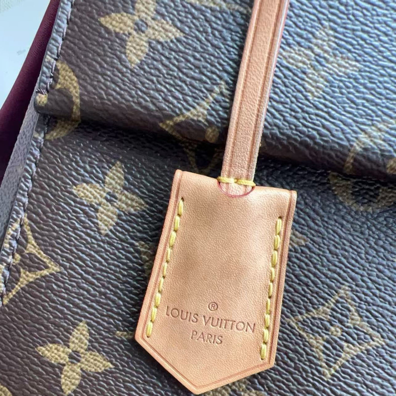 Louis Vuitton leather luggage tag on a monogrammed Louis Vuitton suitcase