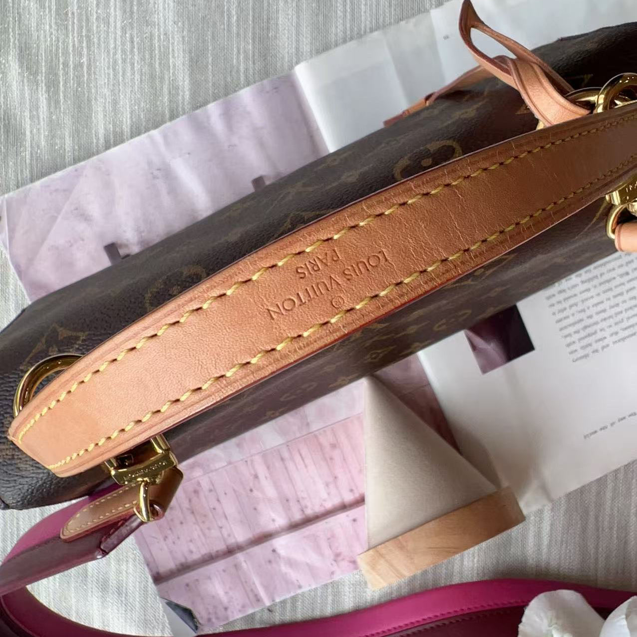Close-up of a Louis Vuitton handbag strap on a textured surface