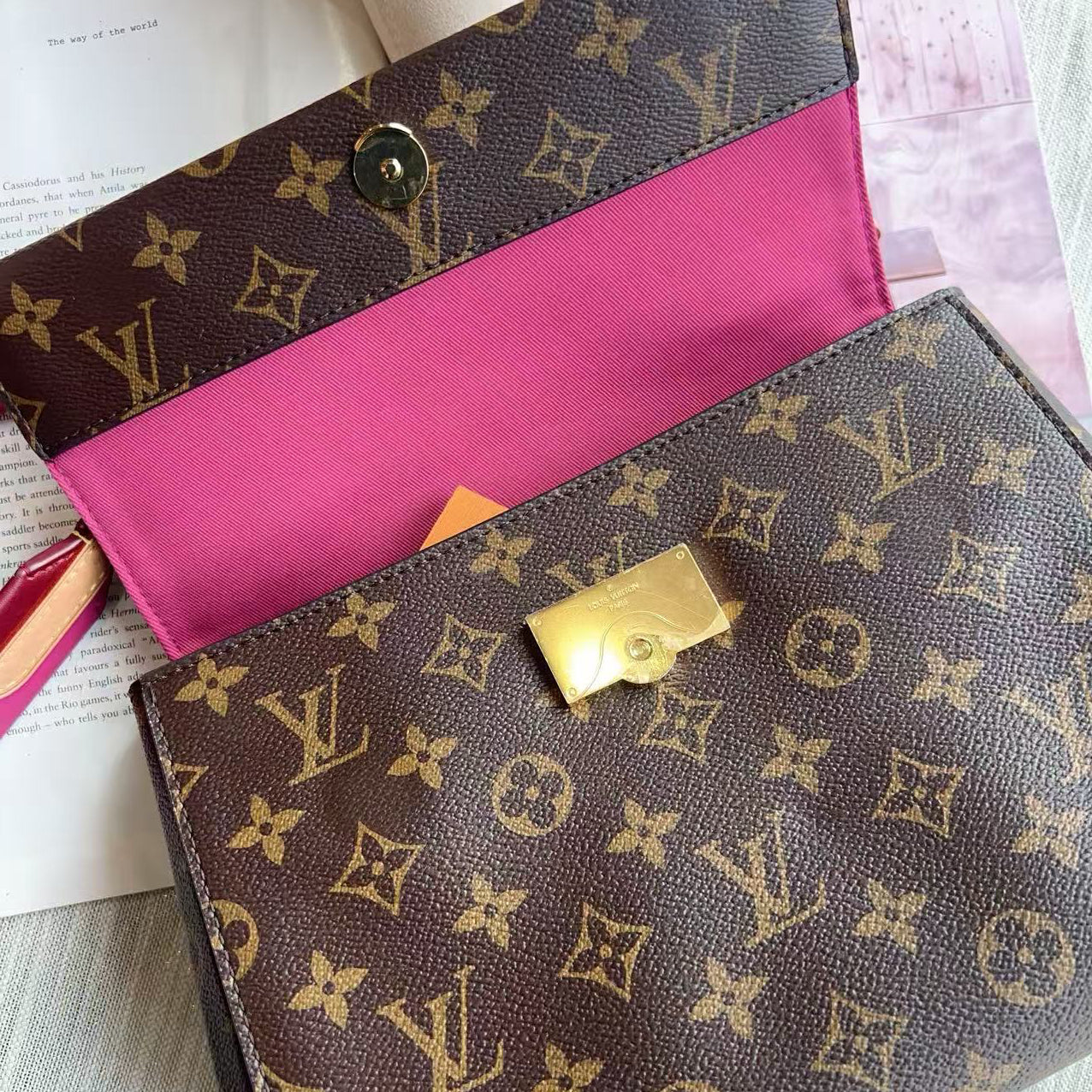 Louis Vuitton monogram handbag with pink interior on a light gray surface