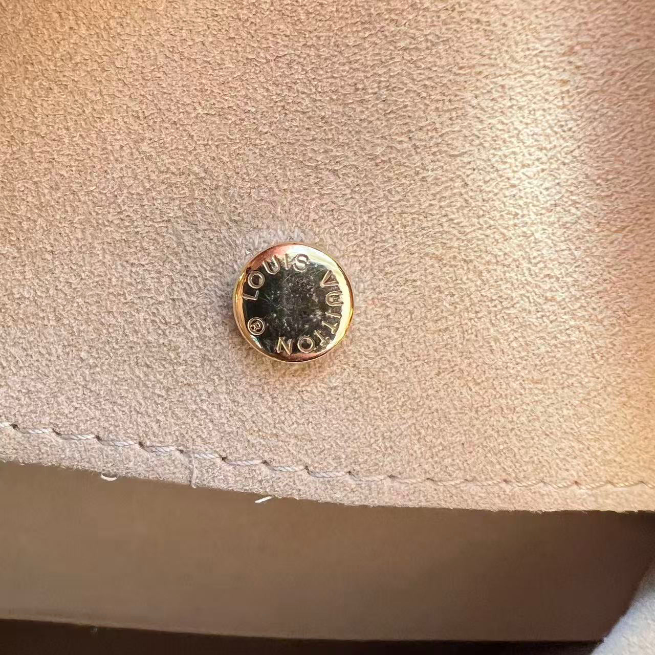 Gold button with 'KORS' branding on a beige fabric surface