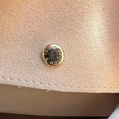 Gold button with 'KORS' branding on a beige fabric surface