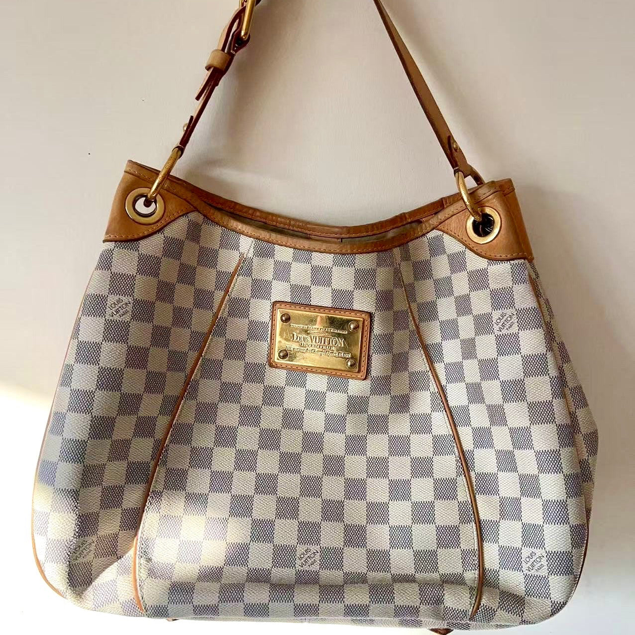Designer handbag with checkered pattern and brown leather accents on a white background