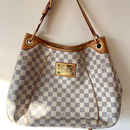 Designer handbag with checkered pattern and brown leather accents on a white background