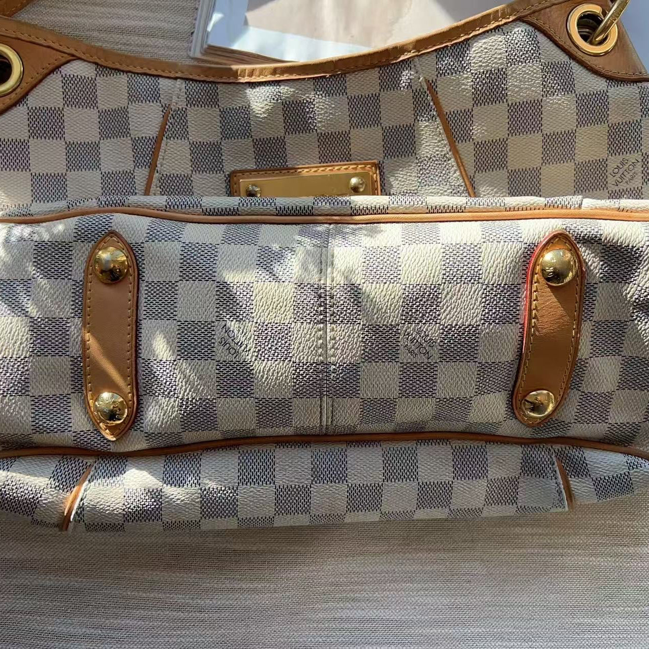 Checkered handbag with brown leather straps on a wooden surface