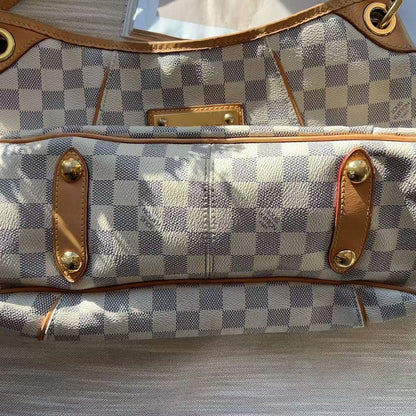 Checkered handbag with brown leather straps on a wooden surface