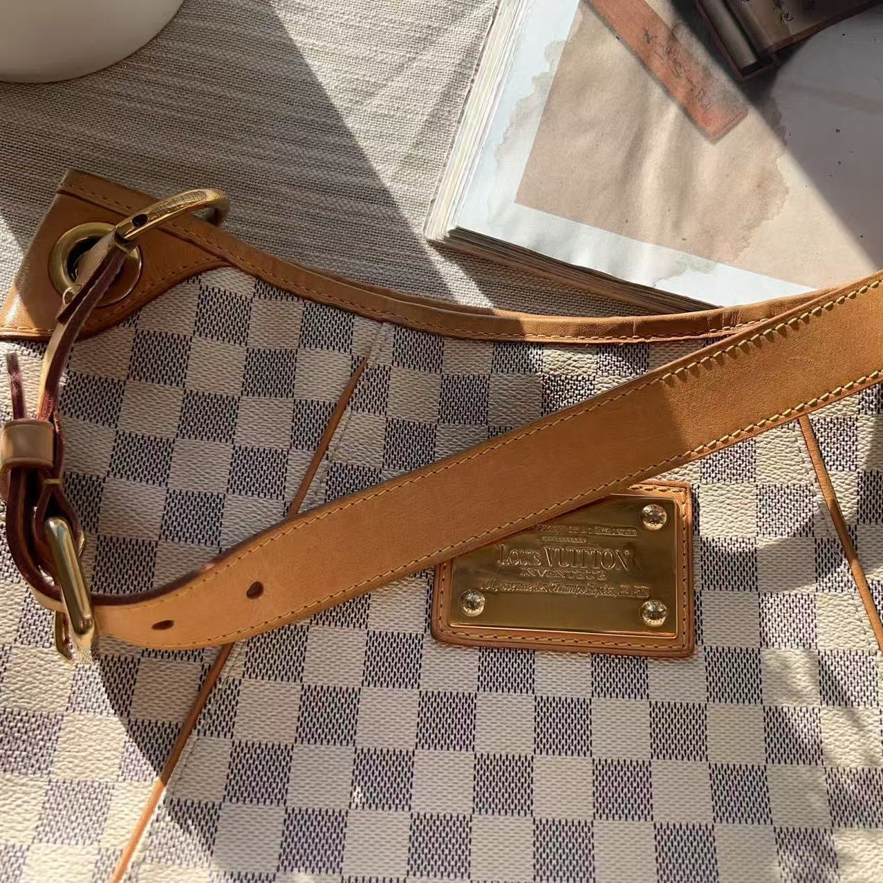 Brown leather strap with gold hardware on a checkered surface