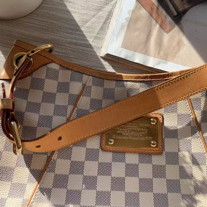 Brown leather strap with gold hardware on a checkered surface