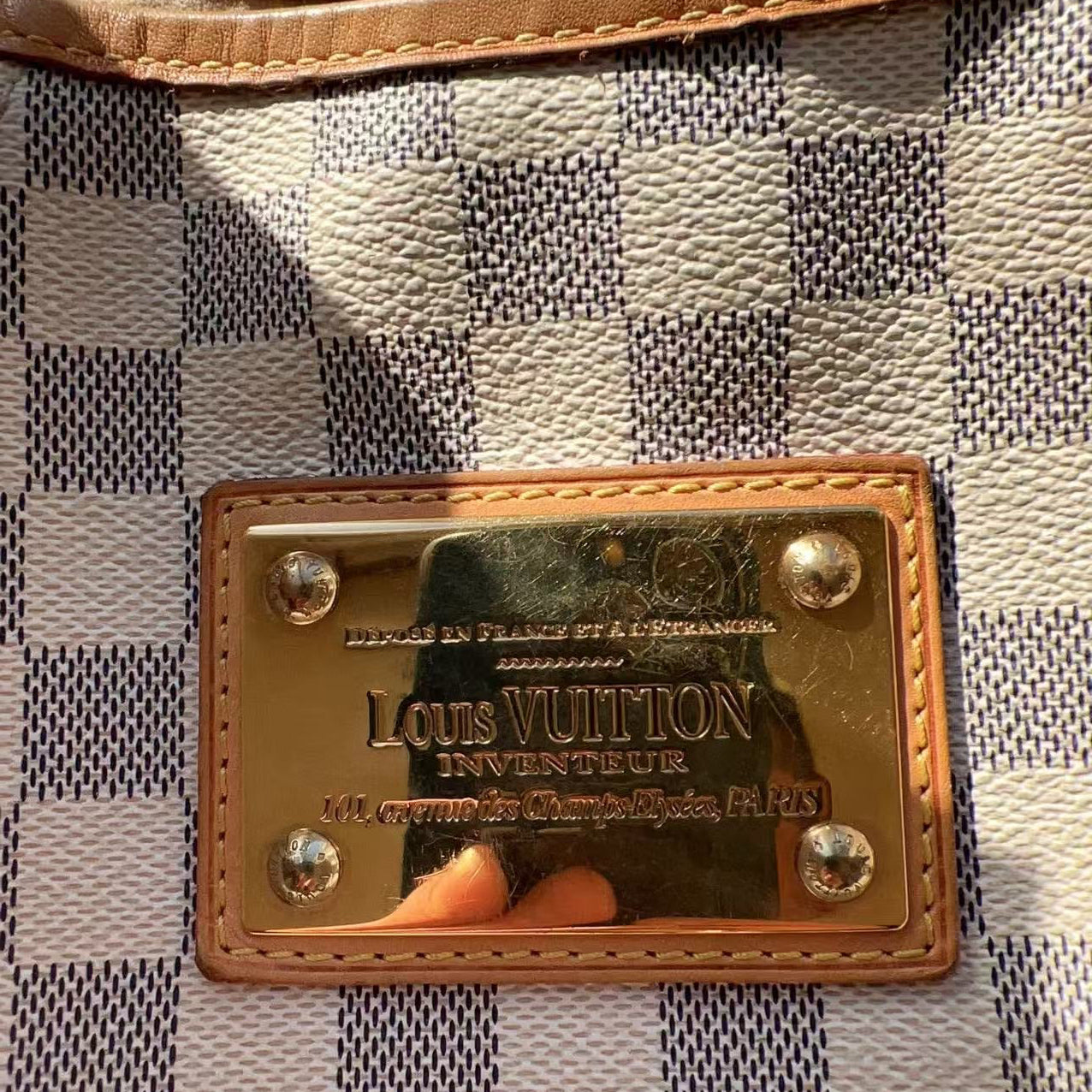 Close-up of a Louis Vuitton plaque on a checkered fabric background