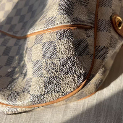 Close-up of a patterned handbag with brown leather accents on a light background