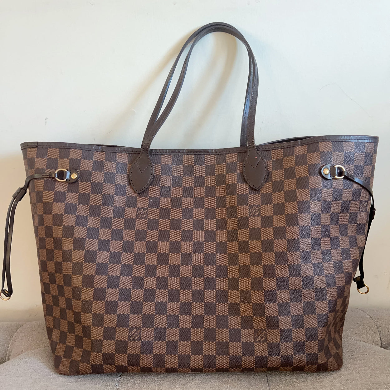 Designer handbag with checkered pattern on a beige couch