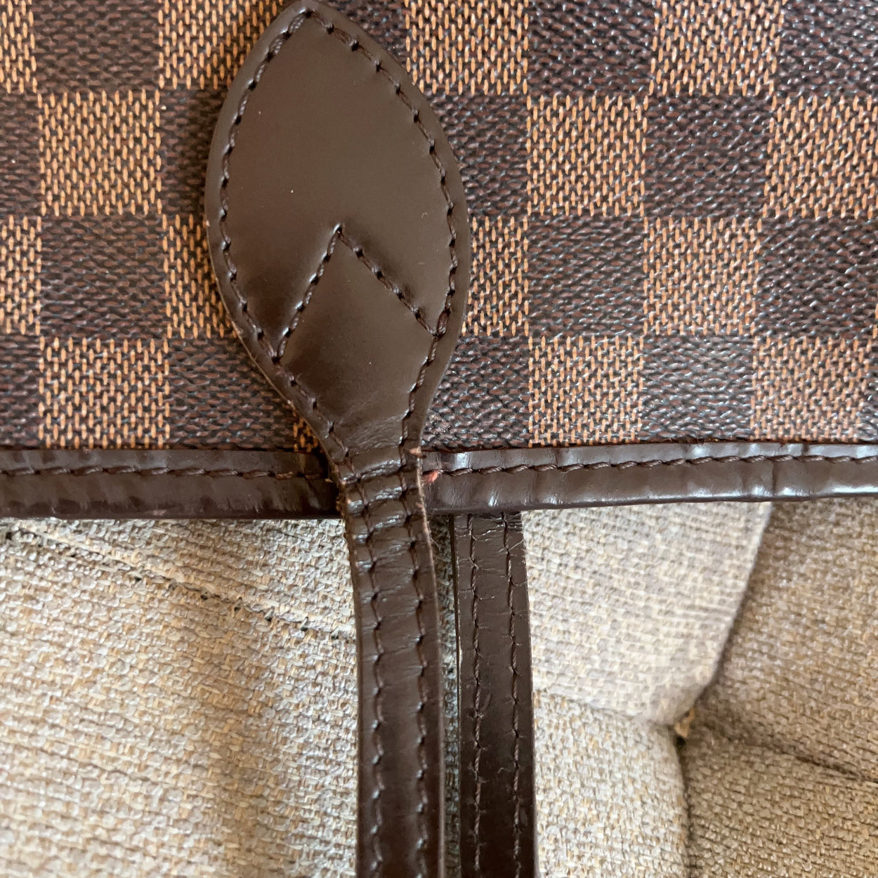 Close-up of a brown and beige checkered handbag with a zipper.