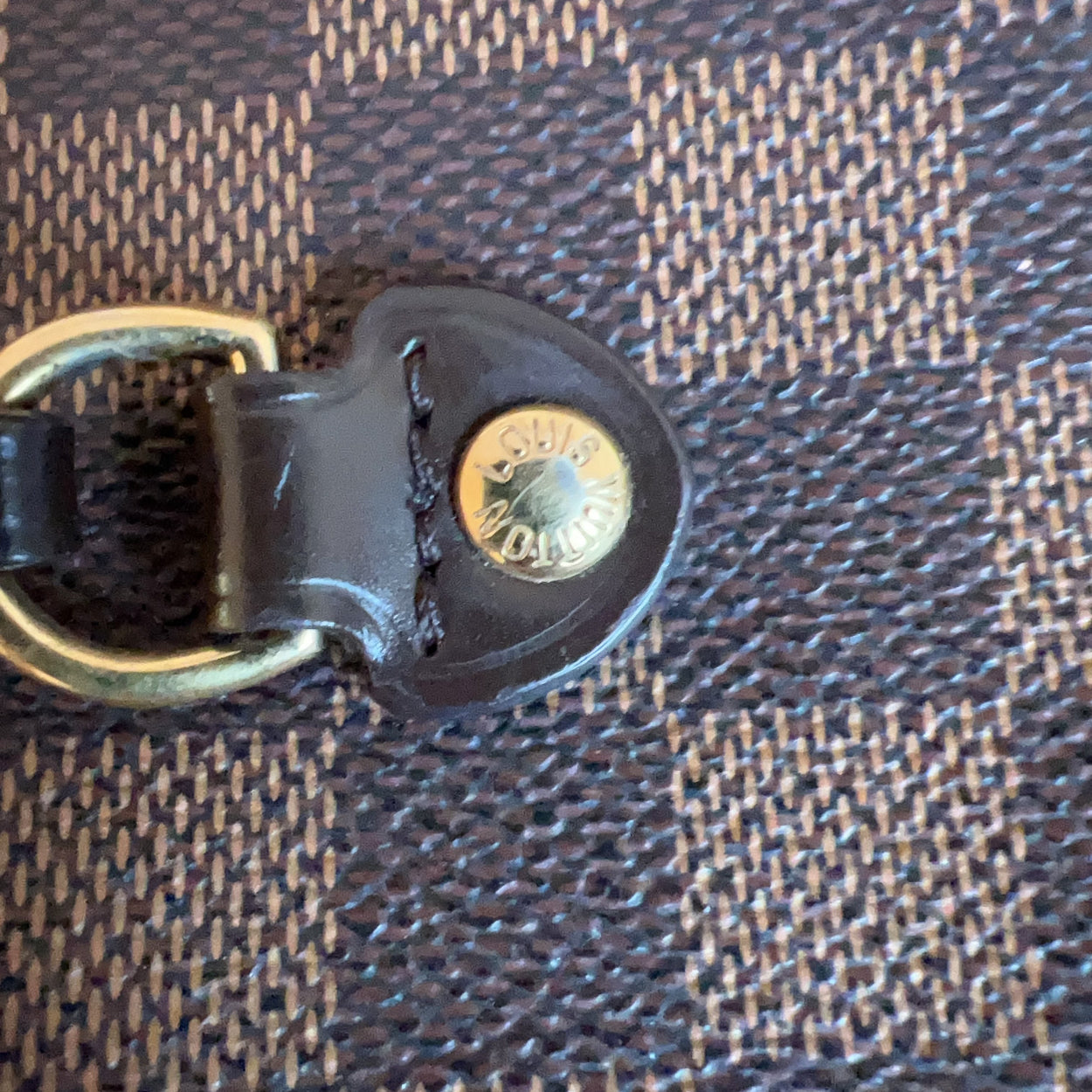 Close-up of a leather strap with a metal ring on a textured fabric background