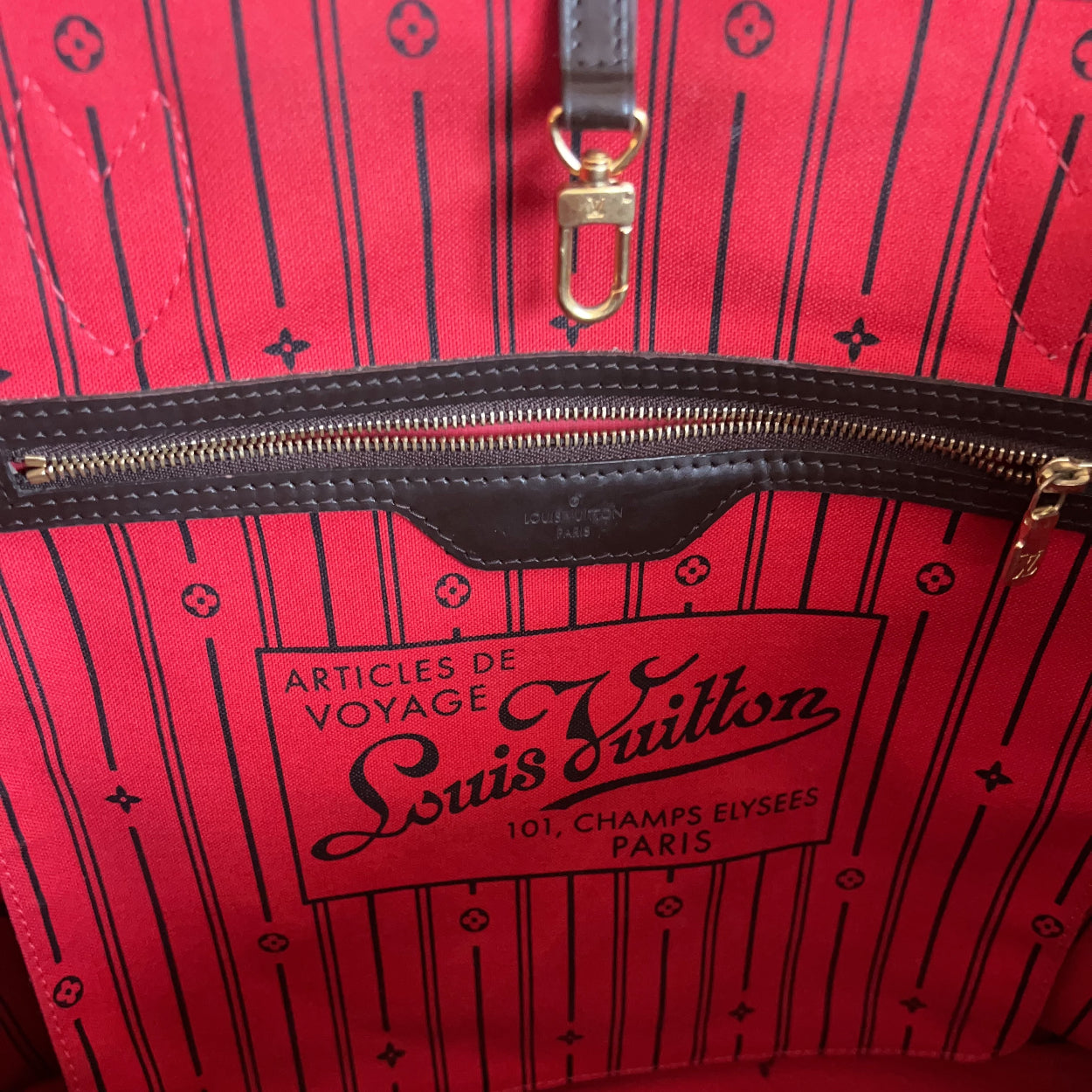 Red Louis Vuitton bag with black pattern and gold zipper.