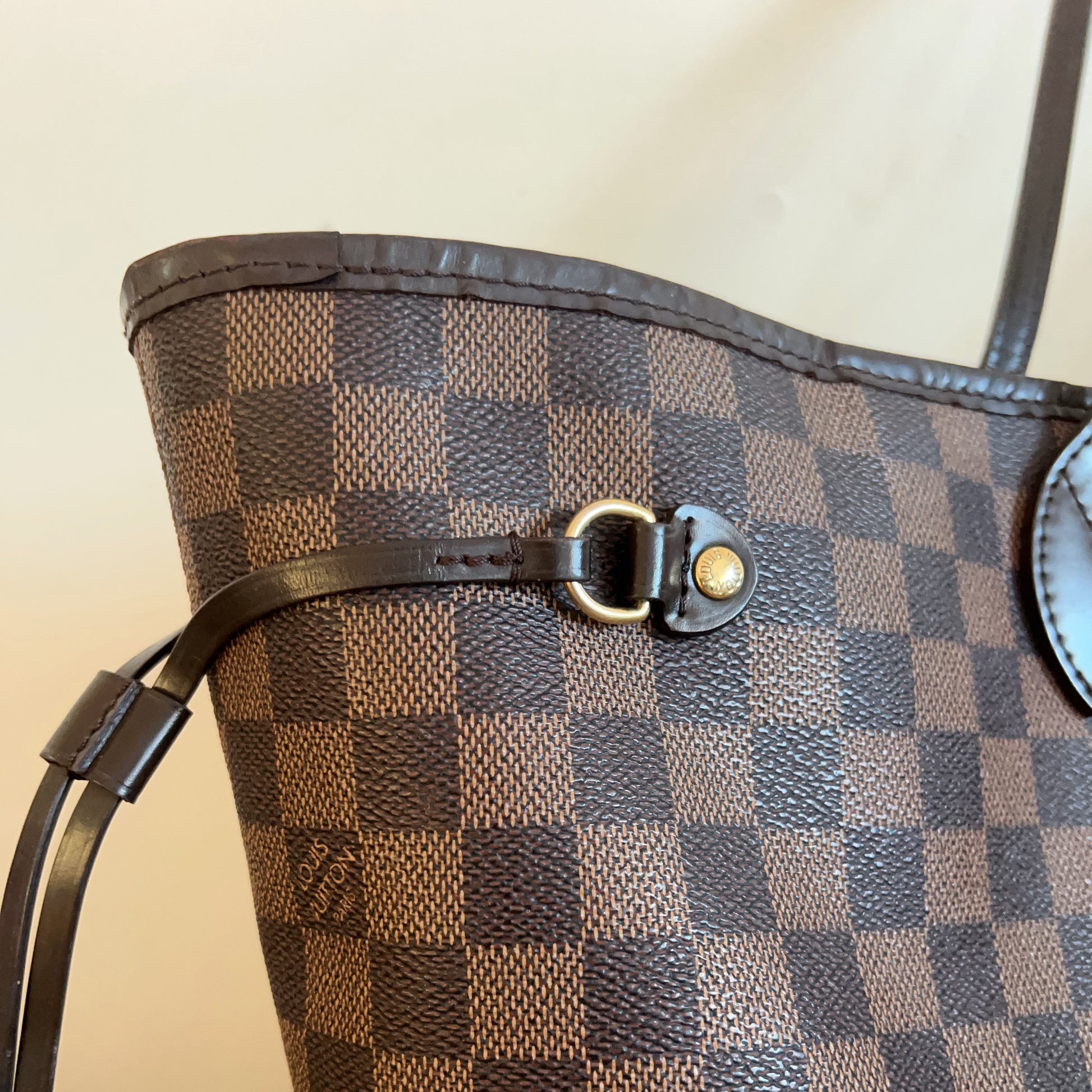 Close-up of a brown and black checkered handbag with a visible brand logo.