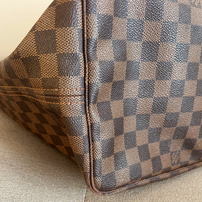 Close-up of a brown checkered handbag on a beige surface
