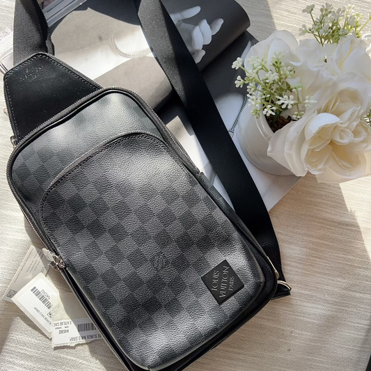 Black checkered crossbody bag on a light wooden surface with flowers in the background