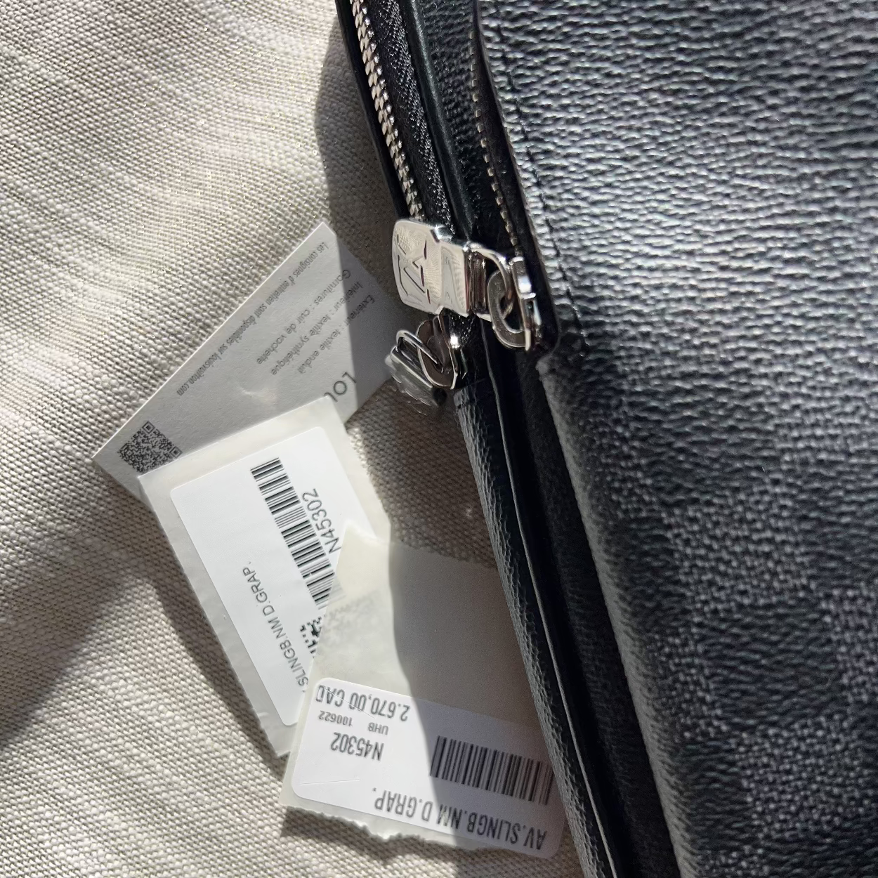Close-up of a gray leather bag with a visible brand tag on a textured surface.