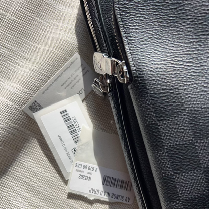Close-up of a gray leather bag with a visible brand tag on a textured surface.